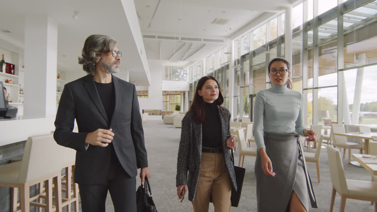 Three business colleagues walking and talking in a modern hotel lobby or restaurant