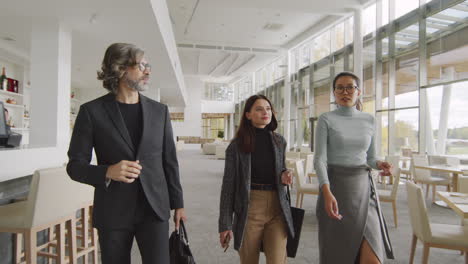 three business colleagues walking and talking in a modern hotel lobby or restaurant