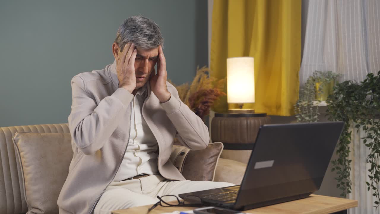 el anciano que trabaja en la computadora portátil tiene dolor de cabeza.