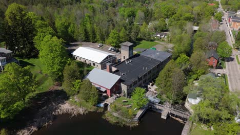 aerial establishing pullback across alton mill in caledon, ontario, surrounded by trees and water above dam