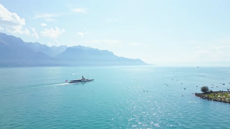 big white boat cruising on the lake of geneva with the alps behind