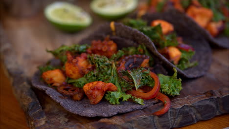 Zeitlupe-Von-Gegrillten-Oktopus-Tacos,-Mariniert-Mit-Traditionellem-Mexikanischen-Adobo,-Serviert-Mit-Salat-Auf-Blauen-Maistortillas