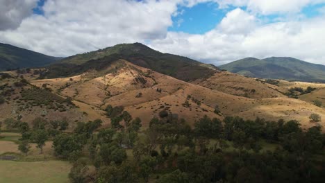 Over-a-creek-and-trees-towards-beautiful-hills-in-the-background-near-Eildon,-Victoria,-Australia