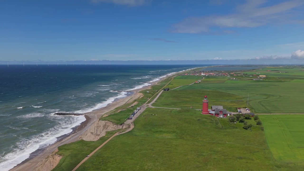 Droneopptak som avslører det røde Bovbjerg fyr midt blant grønne kystenger, ulendte klipper, rullende Nordsjøbølger og det naturskjønne landskapet i Vest-Jylland