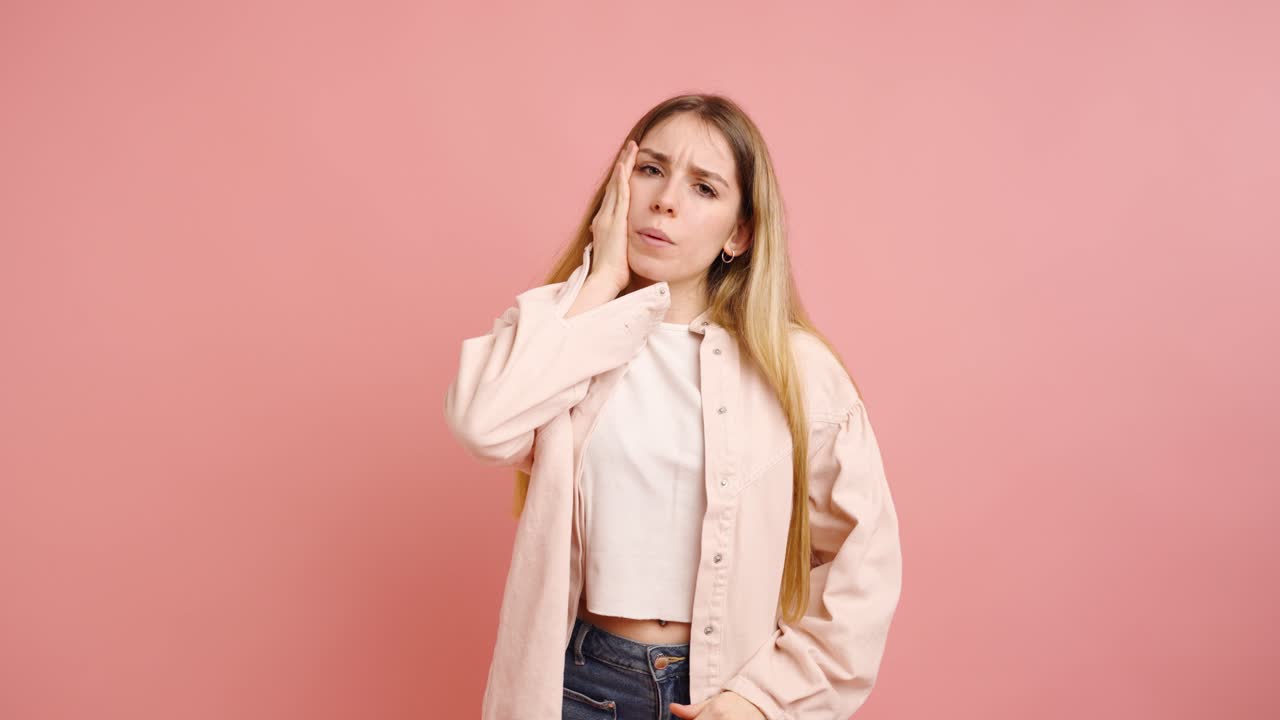 Young woman suffering from headache on pink background
