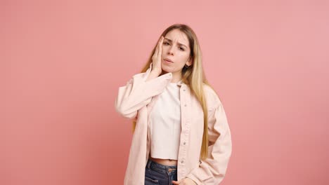 young woman suffering from headache on pink background