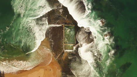 waves crashing around and spilling into a tidal pool at mona vale beach on the northern beaches area of sydney