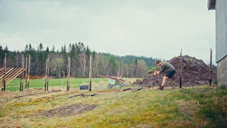time-lapse of a man installing wooden poles deep into the ground in a rural landscape