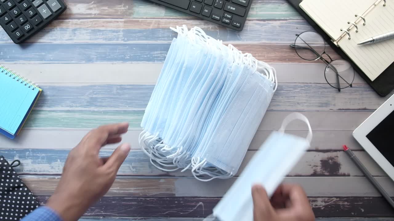 나무 테이블 위 에 마스크 의 어리 를 들고 있는 사람