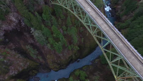 an aerial over a pickup truck traveling over a steel suspension bridge over the skokomish river in washington usa