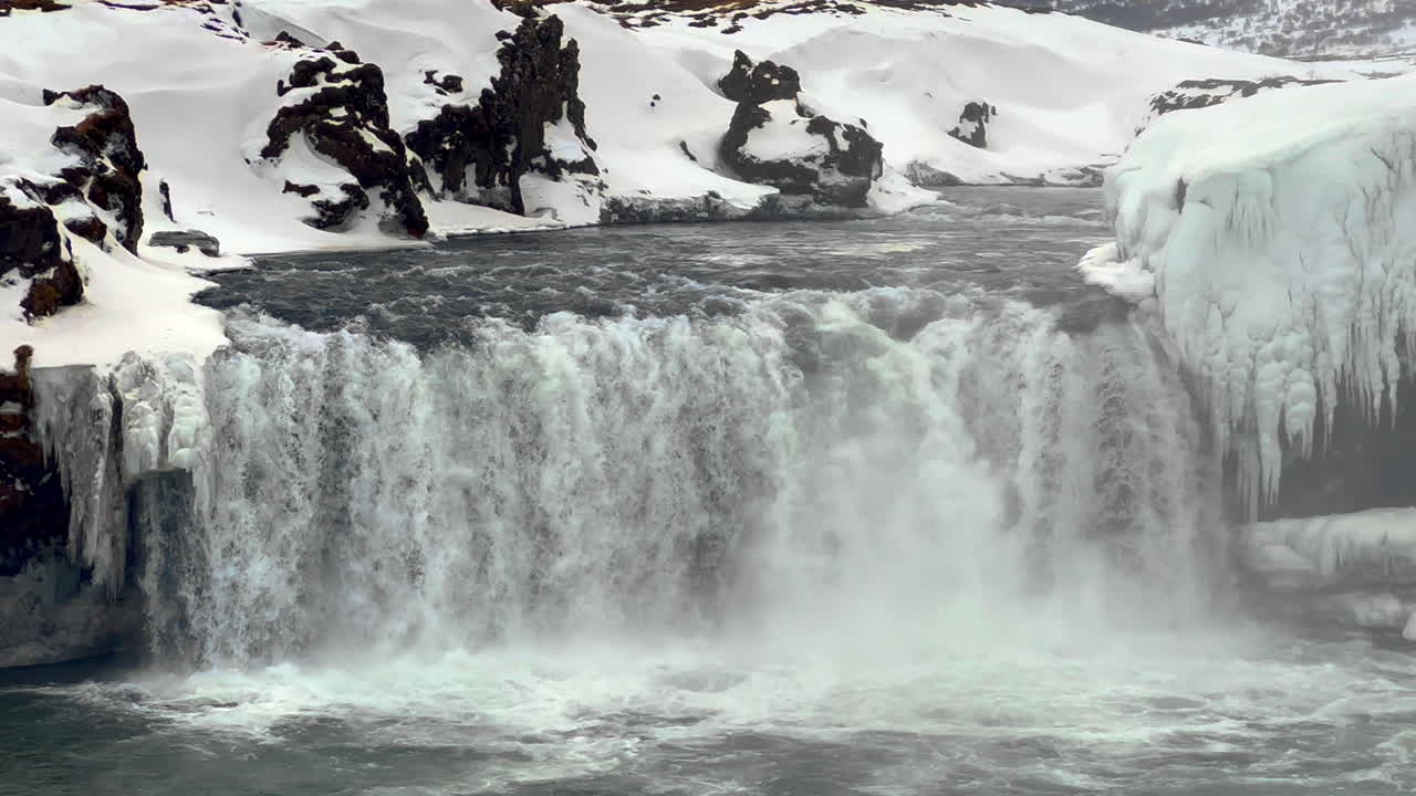 겨울의 goðafoss 폭포, 북쪽 아이슬란드, 바위가 많은 눈 덮인 야생 땅으로 둘러싸인 물의 흐름을 가까이서 볼 수 있습니다.