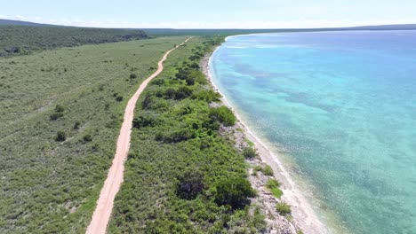 vuelo aéreo sobre un camino de arena a lo largo de la costa de la bahía de pedernales durante un día soleado