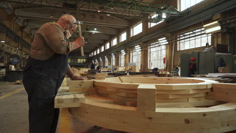 carpintero que ensambla una estructura circular de madera en una gran fábrica