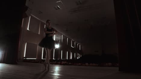 joven bailarina profesional haciendo movimientos circulares en el escenario. hermosa chica bailando en los reflectores por la noche durante el ensayo de traje