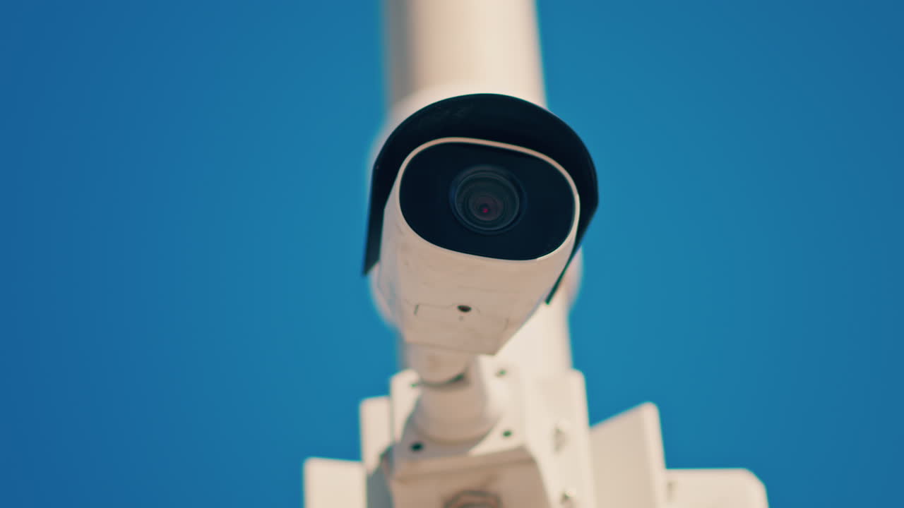 Primo piano di una telecamera di sorveglianza bianca su uno sfondo di cielo blu