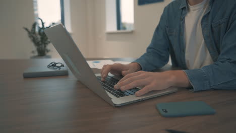 man hands typing on laptop working in office