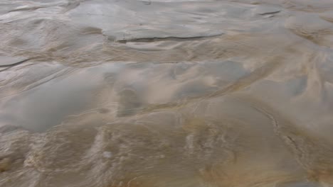 Aguas-Cristalinas-Poco-Profundas-Que-Fluyen-Sobre-Una-Playa-De-Arena-Con-Hermosos-Patrones-Naturales-En-La-Arena-En-Nueva-Zelanda-Aotearoa