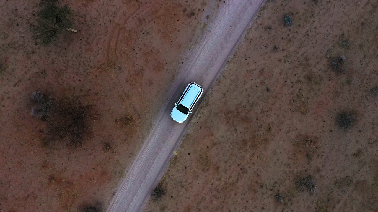 vista aérea por encima de un coche estacionado en una carretera del desierto, por la noche en namibia - de arriba hacia abajo, drone shot