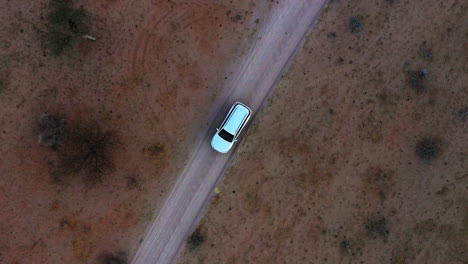 aerial view above a car parked on a desert road, evening in namibia - top down, drone shot