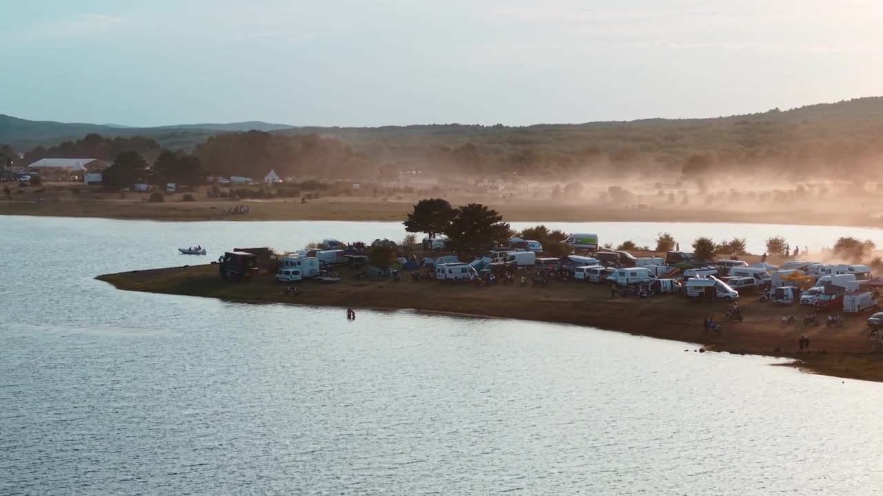 Vista aérea de um parque de campismo movimentado à beira do lago ao pôr do sol