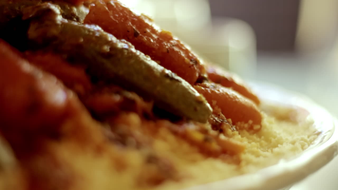 Close-up of a steaming Moroccan couscous topped with colorful vegetables