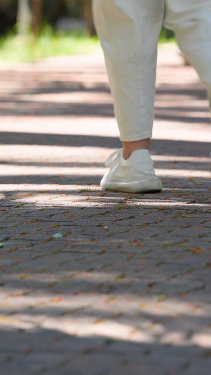 Video verticale: Inizia il tracciamento, jogger con leggings color menta che fa jogging su un sentiero di mattoni, una seconda persona che si allontana