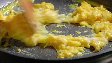 la persona está revolviendo huevos revueltos en una sartén, cocinando huevos para el desayuno