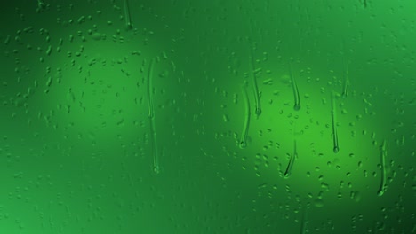 water droplets animation that are slowly trickling down window glass with captured light reflections on their surfaces against an atmospheric green gradient background with highlights