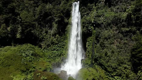 aerial dolly in of salto el leon waterfall falling into a natural pool surrounded by green dense forest, near pucon, chile