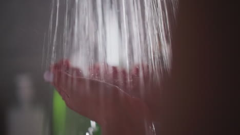 hands of woman immersed in steady water stream. woman relishes warmth with hands catching flowing stream. lady stands in shower cherishing hot water