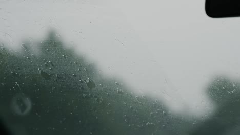 Raindrops-on-windshield-driving-on-highway,-blurred-traffic-background