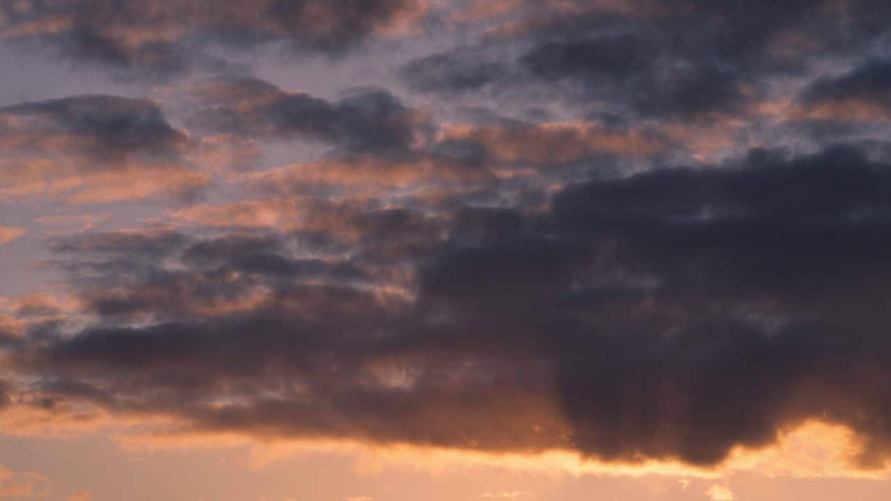 Layered dusk clouds stretch across the sky during golden hour with glowing soft light, backdrop background