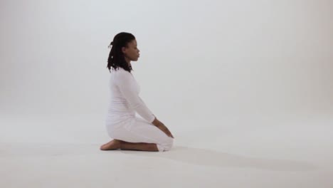 a black yogini peacefully moves into vajrasana or thunderbolt pose