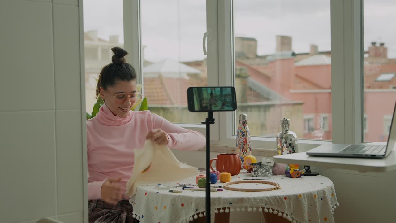 Giovane donna che realizza un vlog su ricamo e artigianato a casa