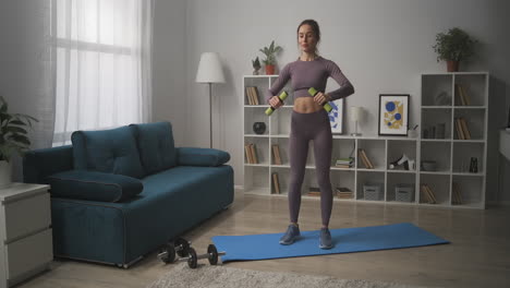 sporty lady with dumbbells in living room home workout for good shape of body sportswoman is lifting weights fitness and wellness