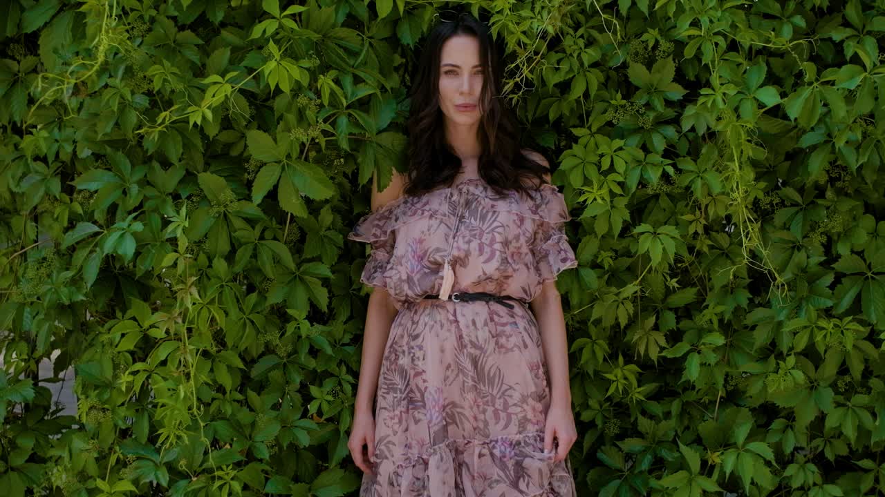 녹색 잎 부시 배경 위에 포즈 세련 된 hipster 소녀