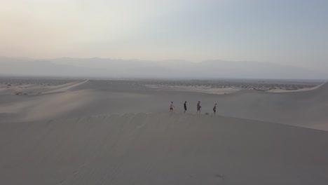 Aerial-Drone-Shot-of-Group-of-People-Walking-on-Sand-Dune-in-Death-Valley