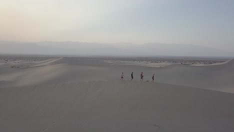 toma aérea de un grupo de personas caminando sobre una duna de arena en el valle de la muerte