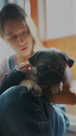 girl holding a pug puppy