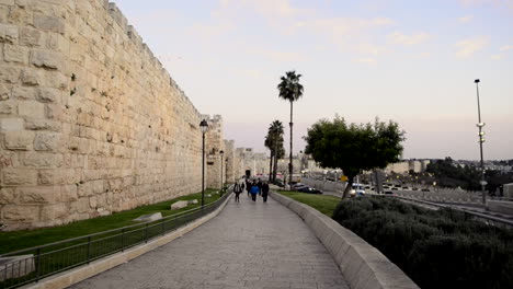 old fortified wall in the ancient holy city of jerusalem, israel. entrance to old city. people and birds passing by