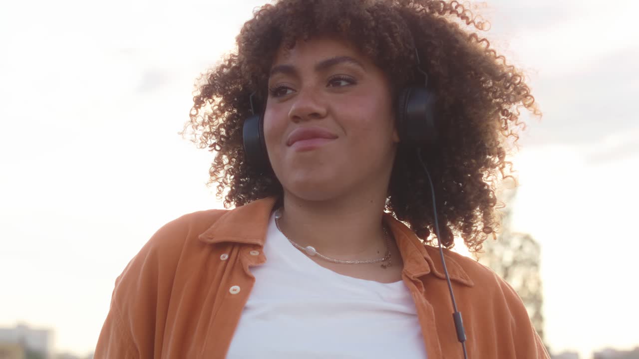 Mulher negra usando fones de ouvido e dançando na ponte