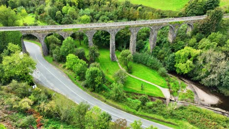 aerial view of stone arch bridge over river in green landscape