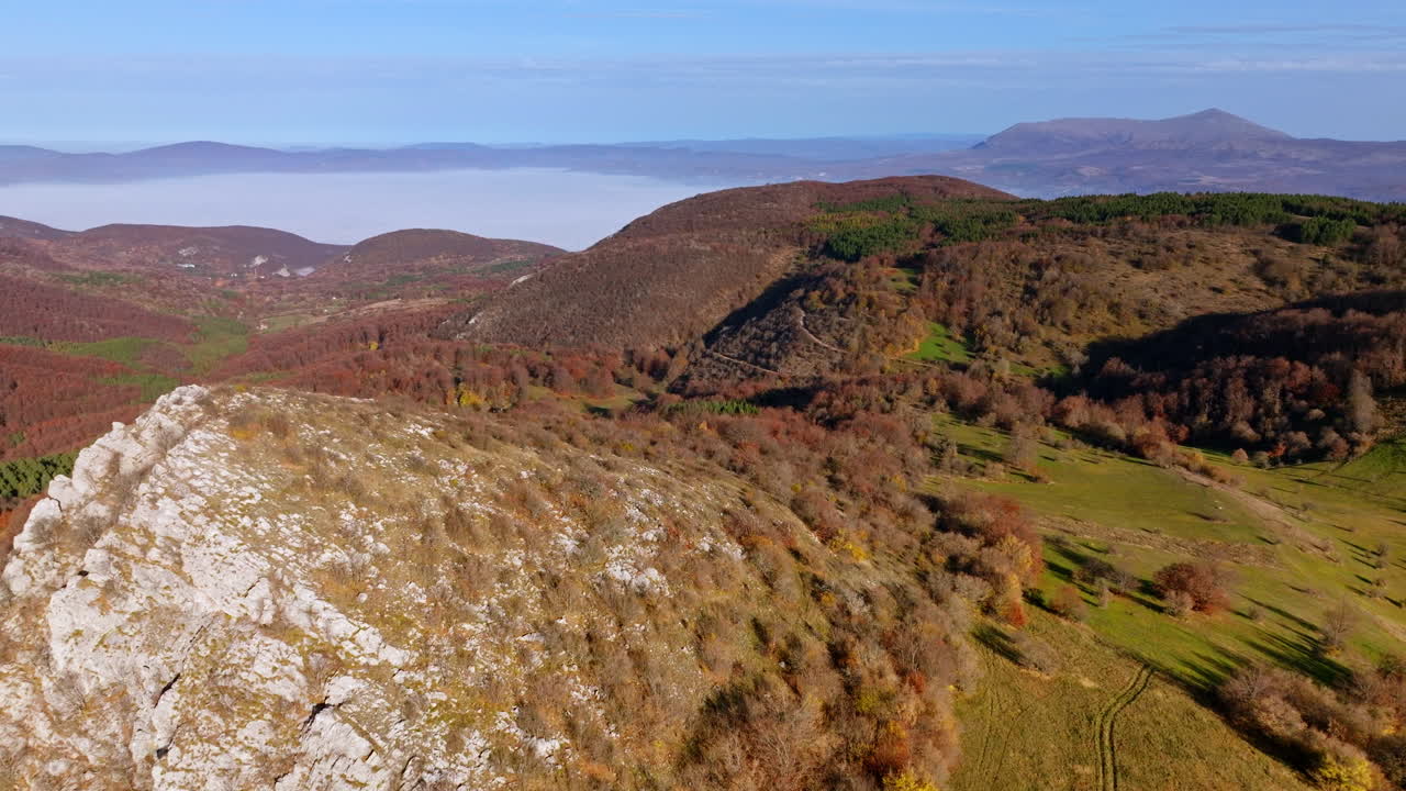 Paesaggio montano autunnale con valle nebbiosa e colori autunnali vivaci