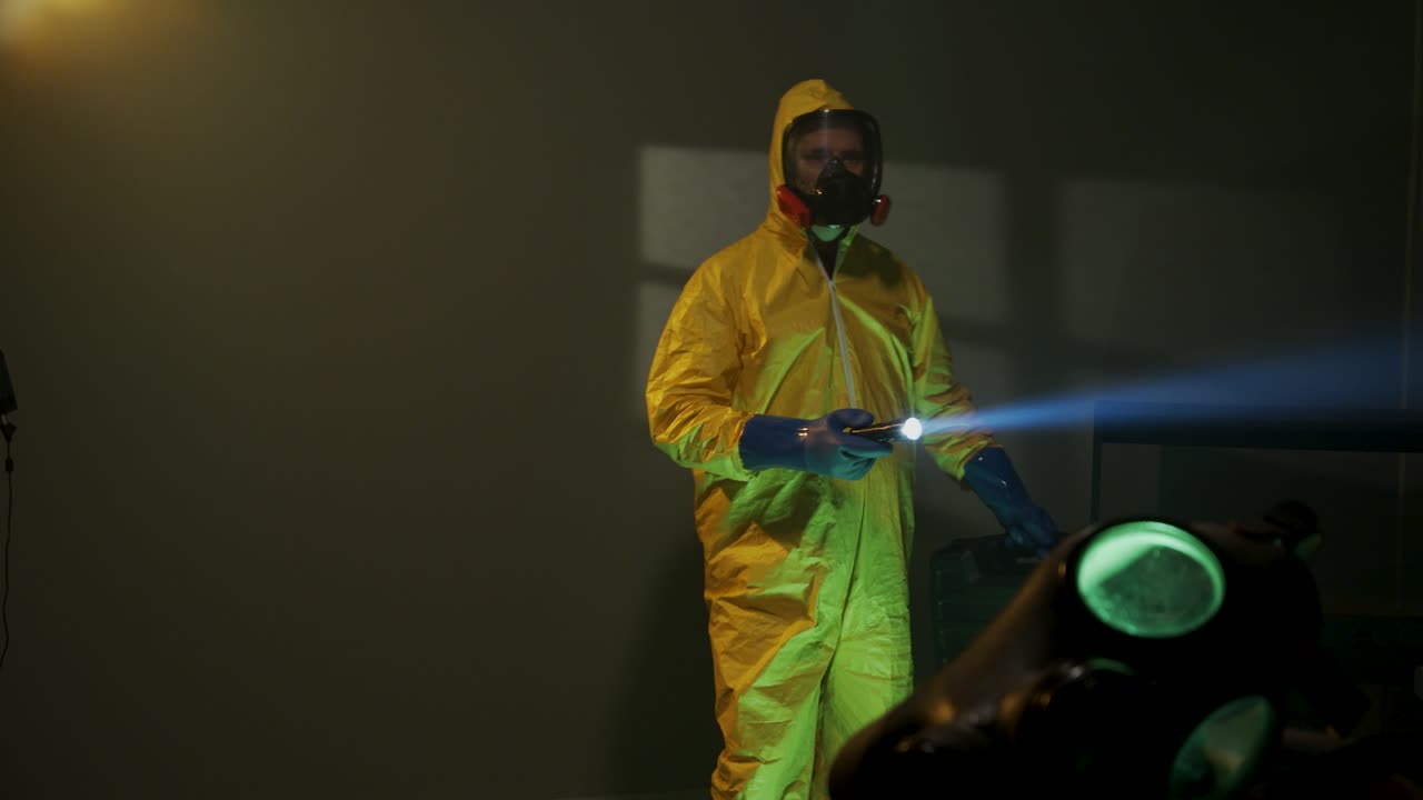 Hazmat suit wearing man explores a dark room