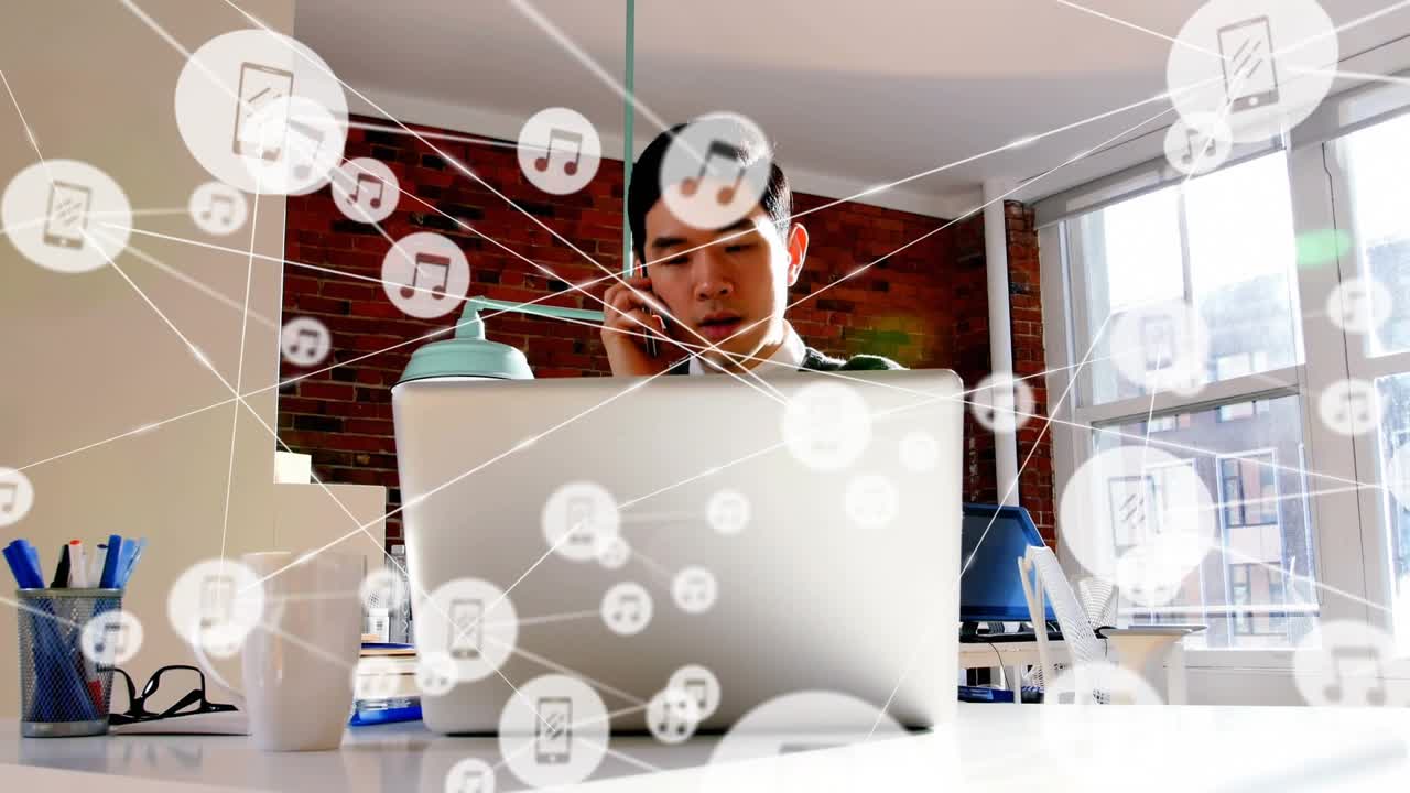 Man taking phone call after icons appearing, referencing laptop while working, technology overlay