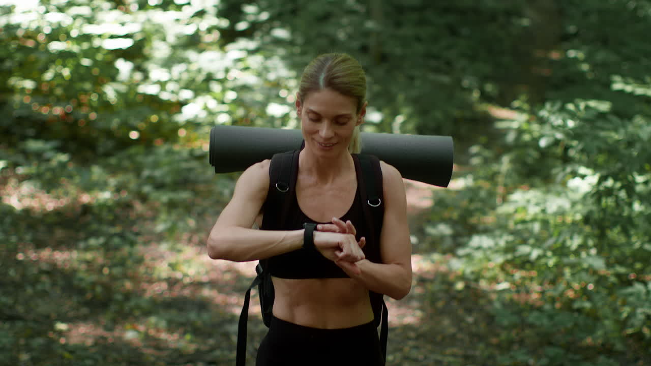Woman checking smartwatch while hiking in a forest