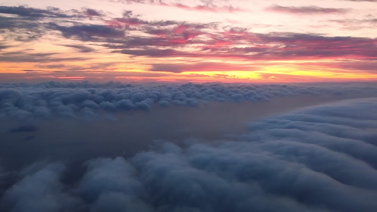 descendiendo a las nubes con un mar debajo y una colorida puesta de sol sobre el horizonte