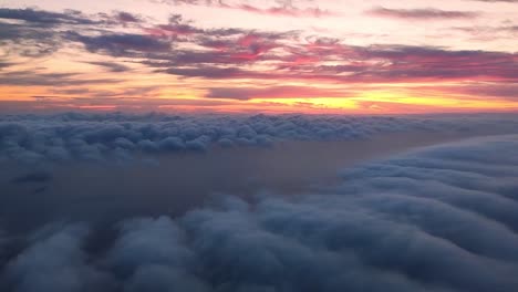 descending to the clouds with a sea beneath it and a colorful sunset above the horizon