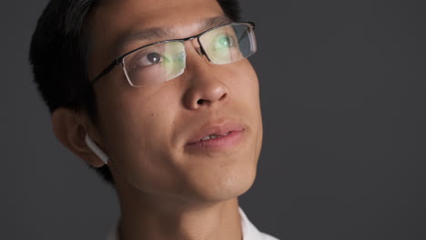 asian man in earphones listening to music on smartphone.