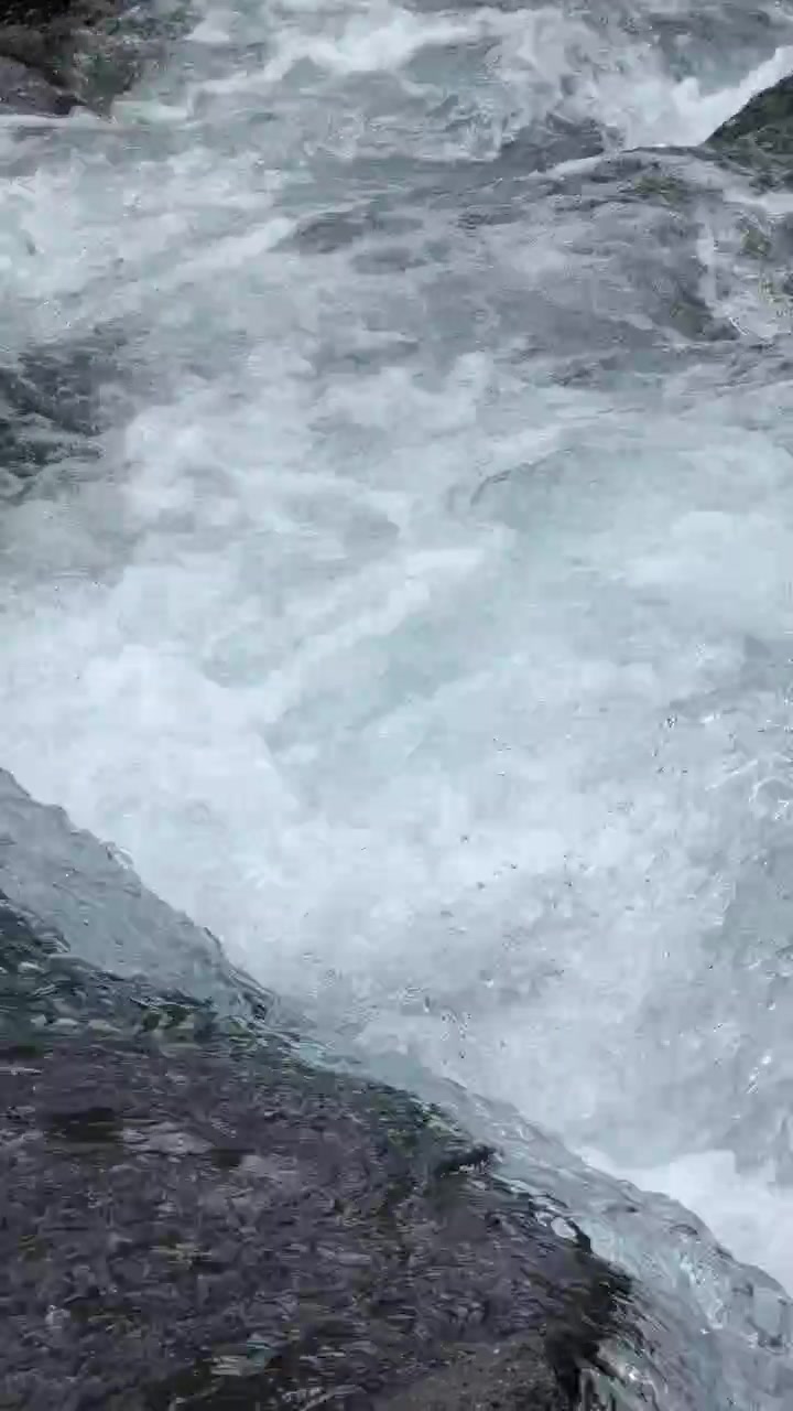 Acqua impetuosa che scorre su rocce scure in un ruscello di montagna